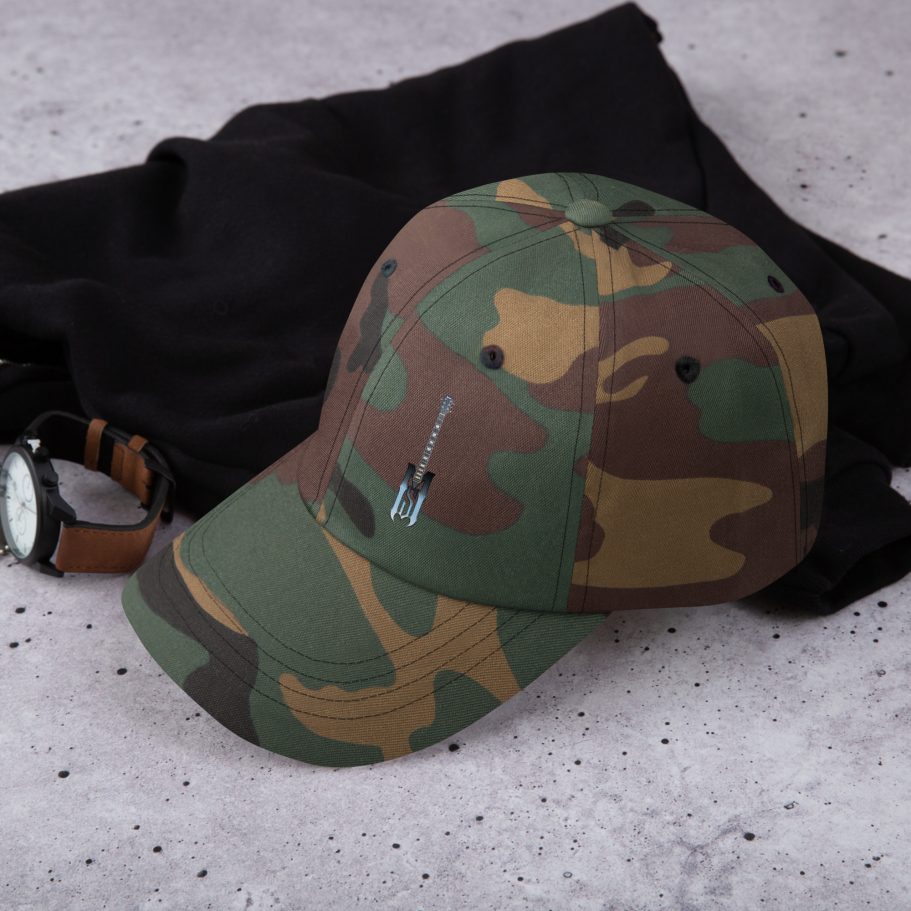 Camo baseball cap placed on a black fabric with a watch beside it.